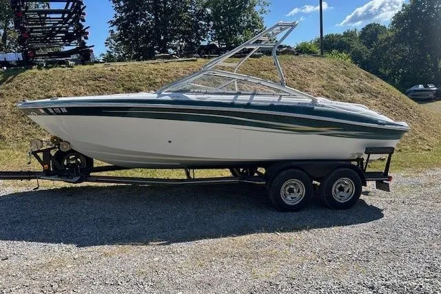 The Image of 2006 Four Winns H210 boat on trailer, parked outdoors on gravel. - 1