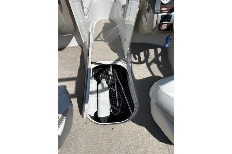 Slide: The Image of 2006 Four Winns H210 boat interior storage compartment with open hatch and visible equipment. - 11