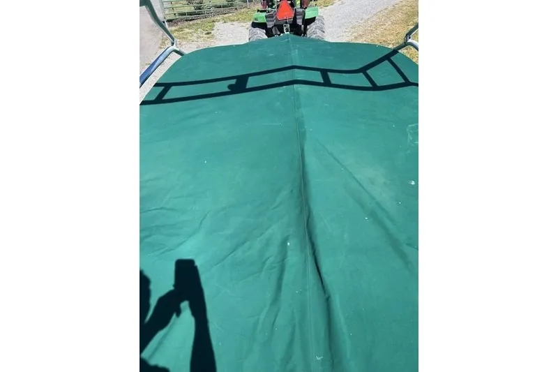 Slide: The Image of Covered Four Winns H210 boat, 2006 model, with green tarp and tractor in background. - 23