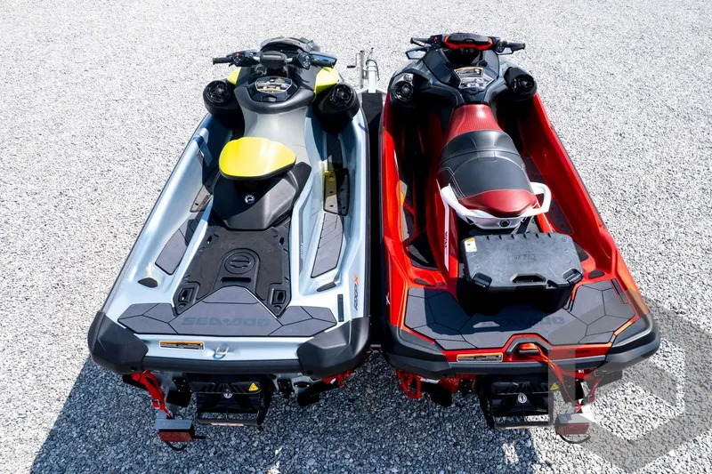 Slide: The Image of 2024 Sea-Doo RXP-X 325 jet skis in gray and red, parked on gravel. - 49