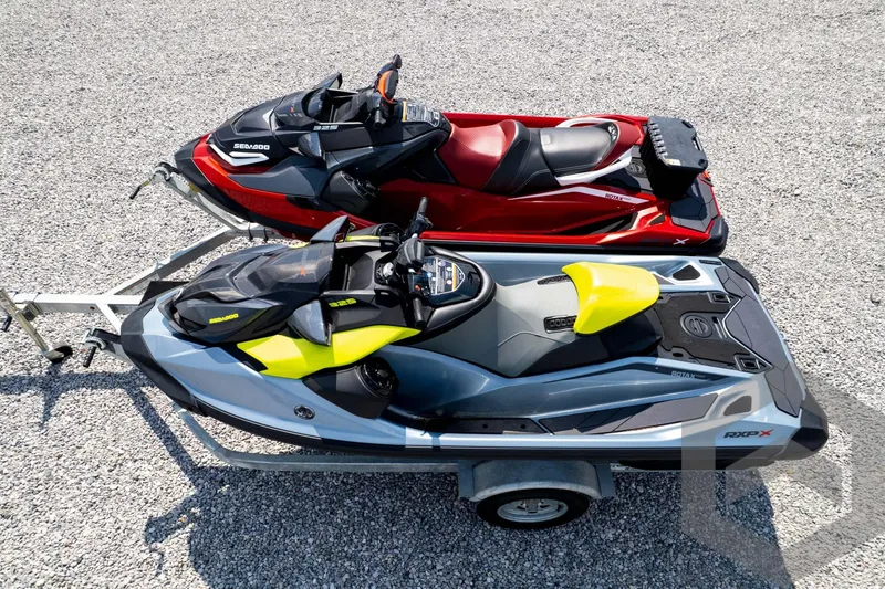 Slide: The Image of 2024 Sea-Doo RXP-X 325 jet skis on trailer, red and yellow models, parked on gravel. - 51