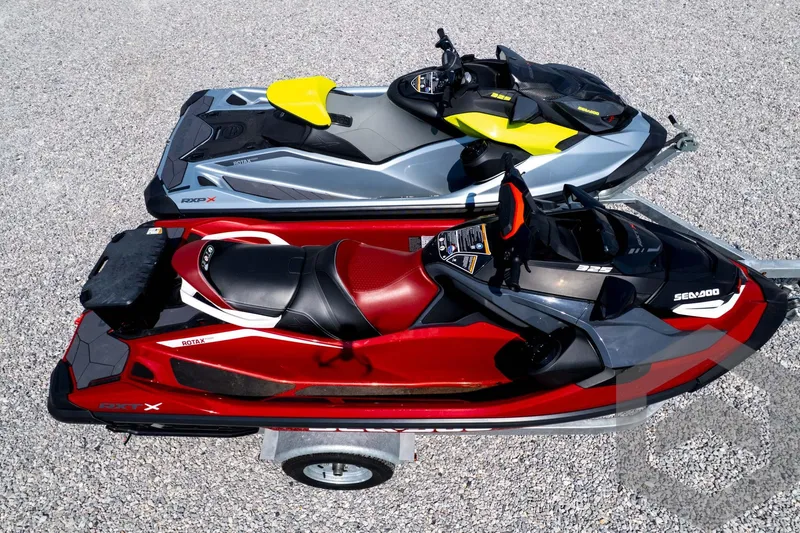 Slide: The Image of 2024 Sea-Doo RXP-X 325 jet skis in red and gray on a gravel surface. - 55