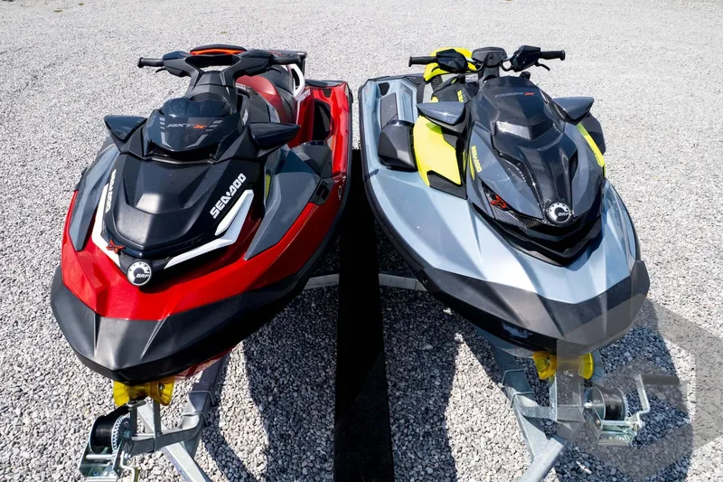 Slide: The Image of 2024 Sea-Doo RXP-X 325 jet skis in red and gray on gravel surface. - 58