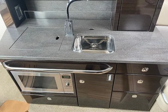 Slide: The Image of 2014 Formula 370 Super Sport yacht kitchenette with sink, microwave, and storage cabinets. - 15
