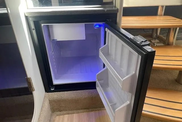 Slide: The Image of Open mini fridge inside 2014 Formula 370 Super Sport boat, with blue interior lighting. - 19