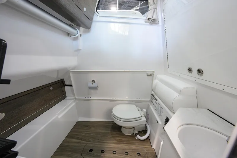 Slide: The Image of 2026 Sportsman Open 322 Center Console boat bathroom with modern amenities and wood accents. - 36