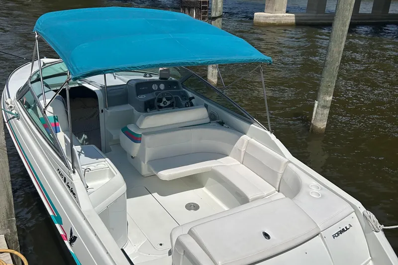 Slide: The Image of 1995 Formula 280 Sun Sport boat with blue canopy docked on water. - 4