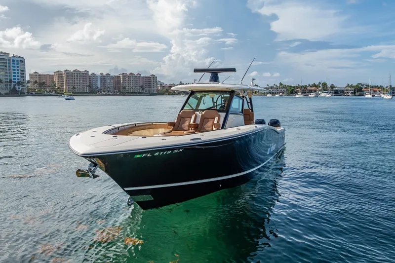 Slide: The Image of 2021 Scout 380 LXF boat on calm water with cityscape background. - 1