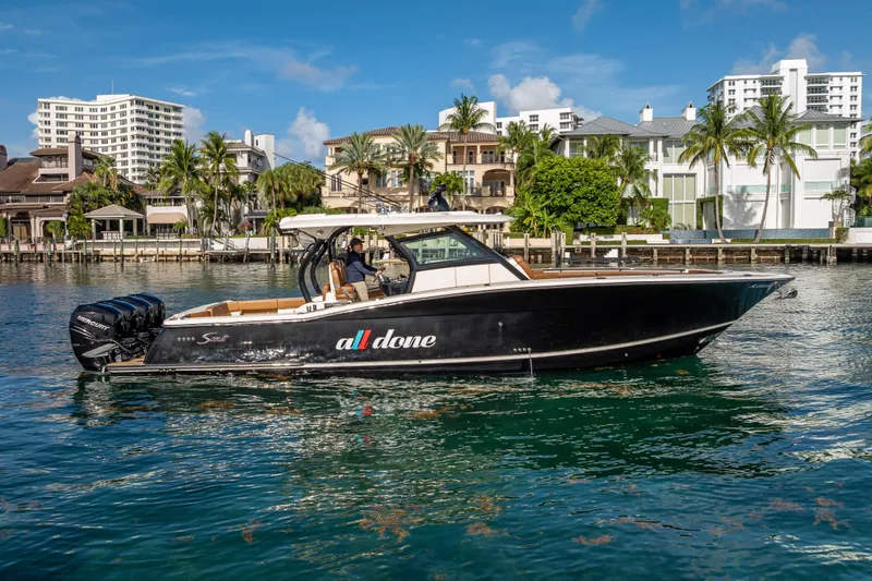 Slide: The Image of 2021 Scout 380 LXF boat cruising near waterfront homes under a clear blue sky. - 12