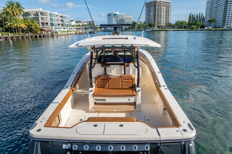 Slide: The Image of 2021 Scout 380 LXF boat on calm water, surrounded by modern buildings and palm trees. - 16
