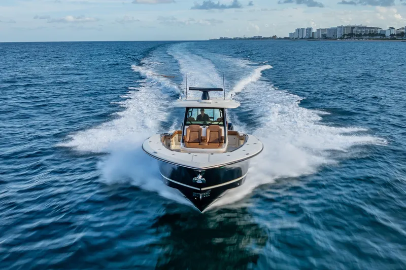 Slide: The Image of 2021 Scout 380 LXF boat cruising on open ocean near city skyline. - 20