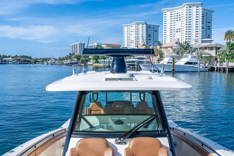 Slide: The Image of 2021 Scout 380 LXF boat cruising in a marina with city skyline backdrop. - 43
