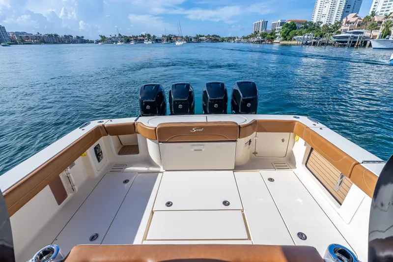 Slide: The Image of 2021 Scout 380 LXF boat deck with four engines, overlooking a scenic waterfront. - 52