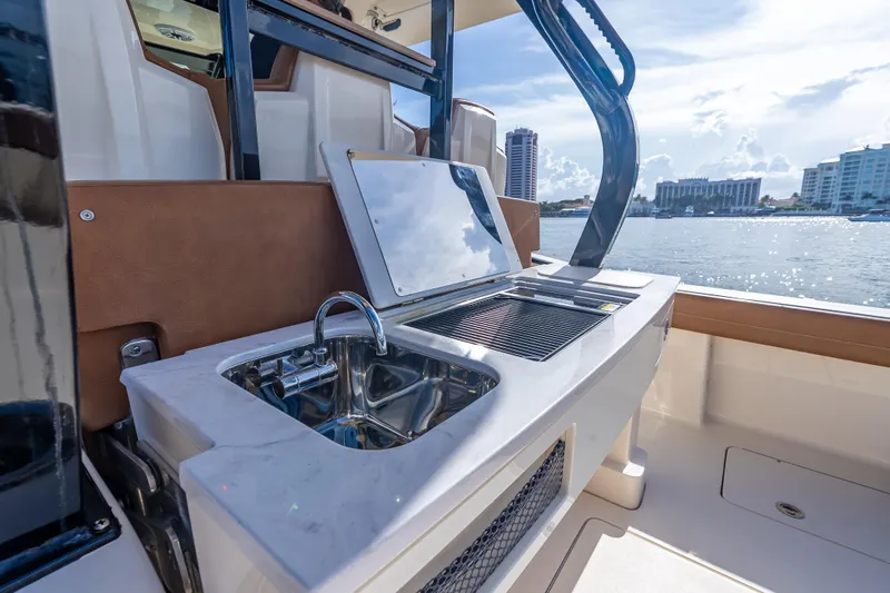 Slide: The Image of 2021 Scout 380 LXF boat with outdoor sink and grill, overlooking waterfront cityscape. - 58