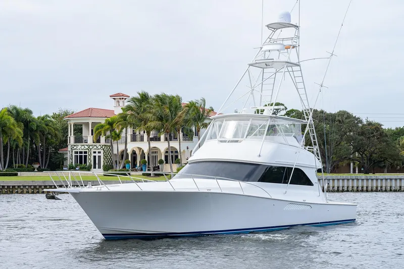 Slide: The Image of 2005 Viking 61 yacht cruising near luxury waterfront mansion with palm trees. - 100