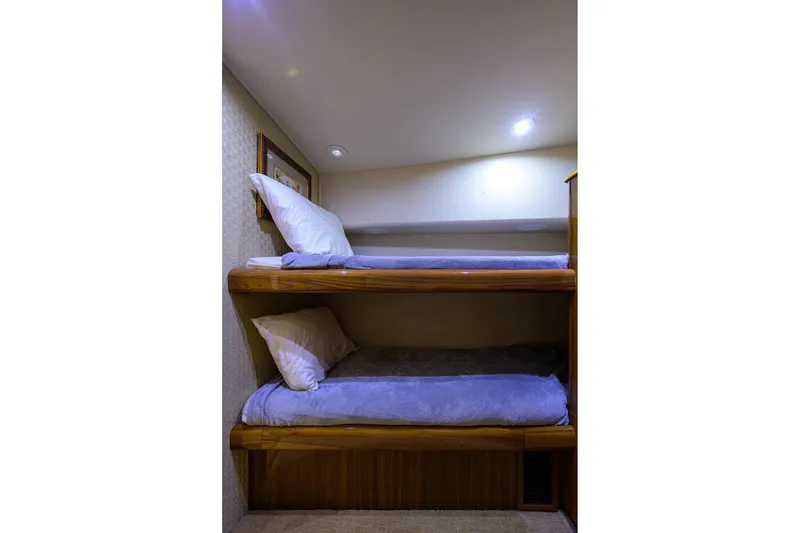 Slide: The Image of Bunk beds in 2005 Viking 61 yacht cabin with soft lighting and cozy bedding. - 13