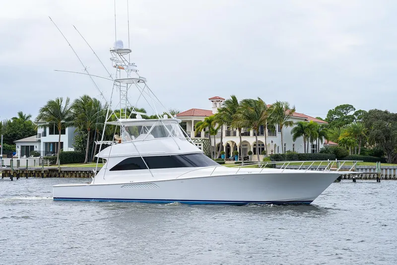 Slide: The Image of 2005 Viking 61 yacht cruising near luxury waterfront homes with palm trees. - 2