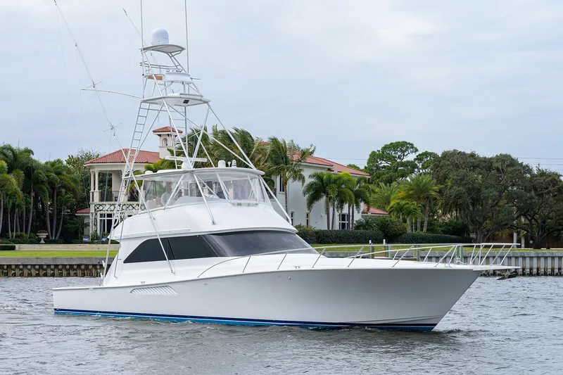 Slide: The Image of 2005 Viking 61 yacht cruising near waterfront homes with lush greenery. - 50