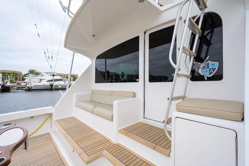 Slide: The Image of 2005 Viking 61 yacht deck with seating, ladder, and marina view. - 79