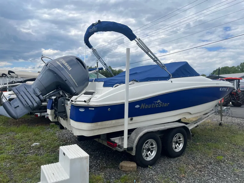 Slide: The Image of 2016 NauticStar 203DC Sport Deck boat on trailer, blue and white design, outdoor setting. - 2