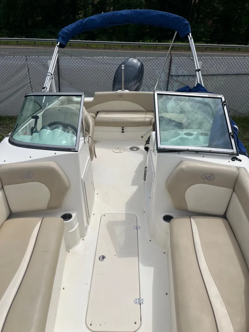 Slide: The Image of 2016 NauticStar 203DC Sport Deck boat with beige seating and blue canopy. - 7