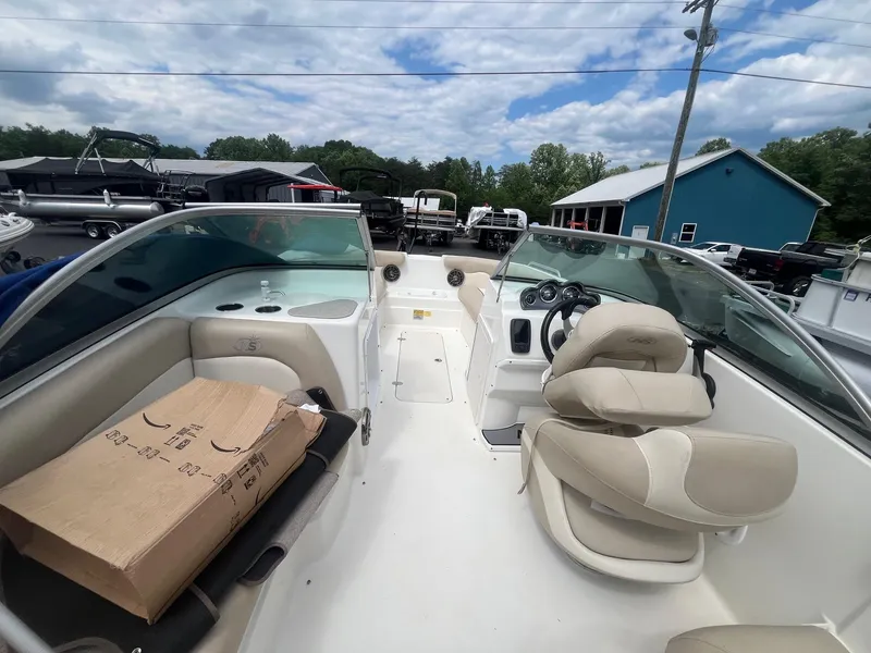 Slide: The Image of 2016 NauticStar 203DC Sport Deck boat interior with seating and console, parked outdoors. - 8