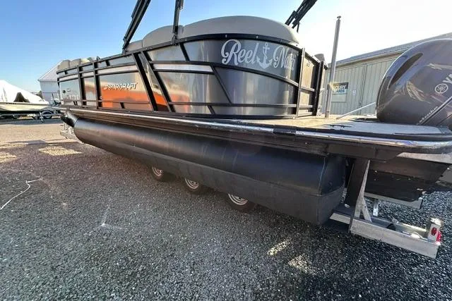 Slide: The Image of 2021 Starcraft SLS 1 pontoon boat on gravel, side view with visible motor. - 7