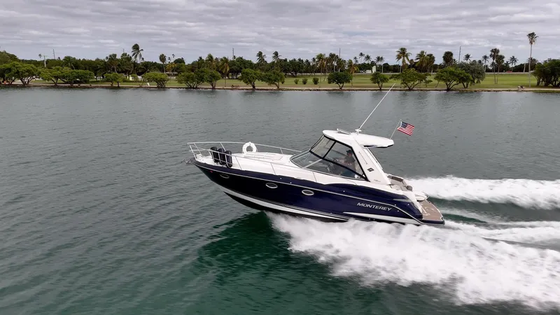 Slide: The Image of 2015 Monterey 335 Sport Yacht cruising on a scenic waterway with lush greenery. - 24