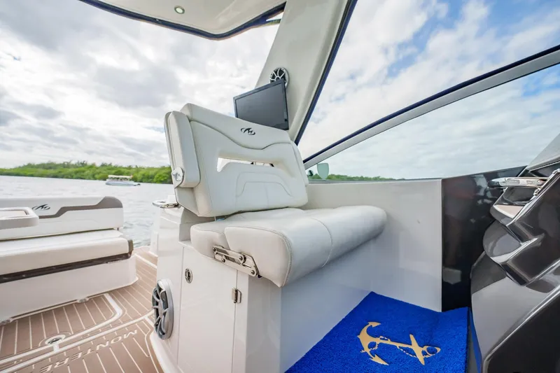 Slide: The Image of 2015 Monterey 335 Sport Yacht interior with white seating and blue anchor-themed mat. - 25