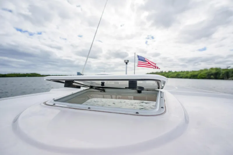 Slide: The Image of 2015 Monterey 335 Sport Yacht with open hatch and American flag on a cloudy day. - 34