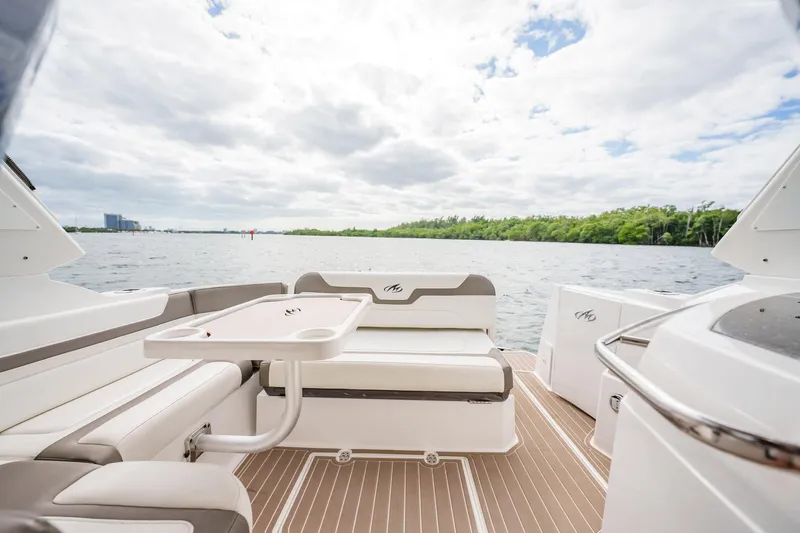 Slide: The Image of 2015 Monterey 335 Sport Yacht interior with seating and table, overlooking serene water and lush greenery. - 39