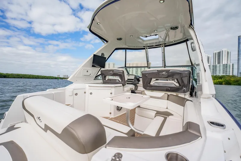 Slide: The Image of 2015 Monterey 335 Sport Yacht interior with seating, table, and city skyline in background. - 43