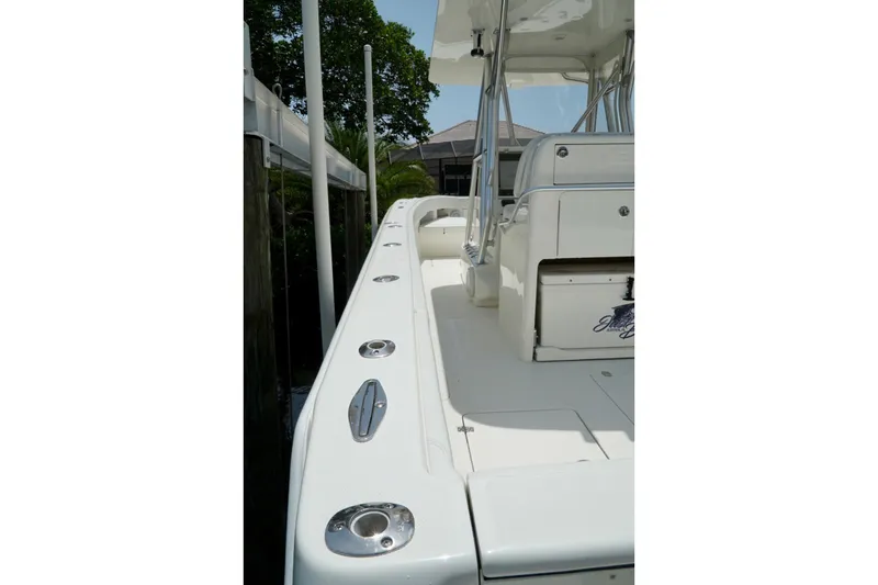 Slide: The Image of 2017 SeaVee 34Z boat deck with seating and rod holders, docked near greenery. - 94