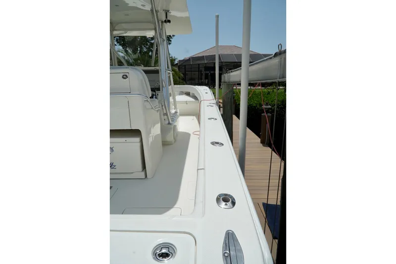 Slide: The Image of 2017 SeaVee 34Z boat deck with seating and rod holders, docked near a house. - 95