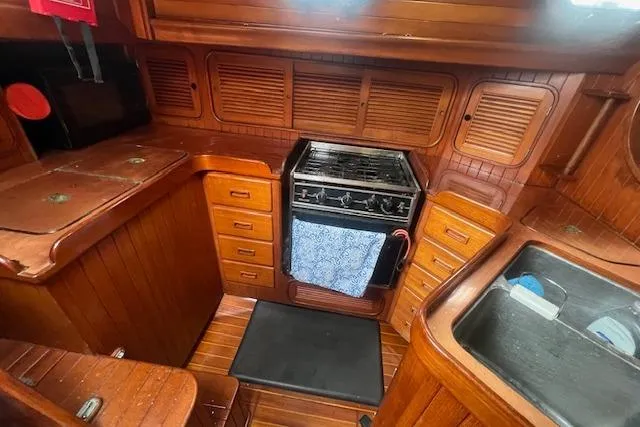Slide: The Image of 1983 Baba 40 yacht interior with wooden cabinetry, stove, and sink. - 10