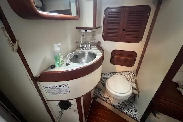 Slide: The Image of 1983 Baba 40 yacht bathroom with sink, toilet, and wooden accents. - 14