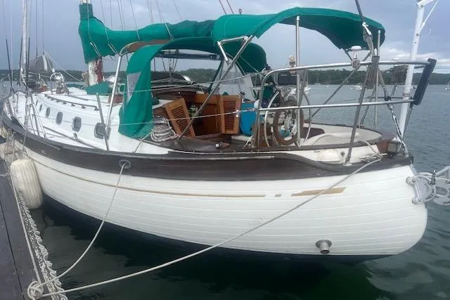 Slide: The Image of 1983 Baba 40 sailboat with green canopy, docked on calm water. - 41