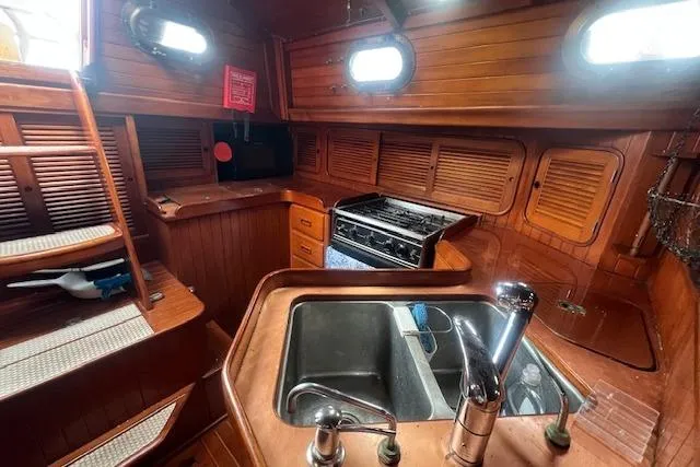 Slide: The Image of 1983 Baba 40 yacht interior with wooden cabinetry, sink, and stove in the galley area. - 9