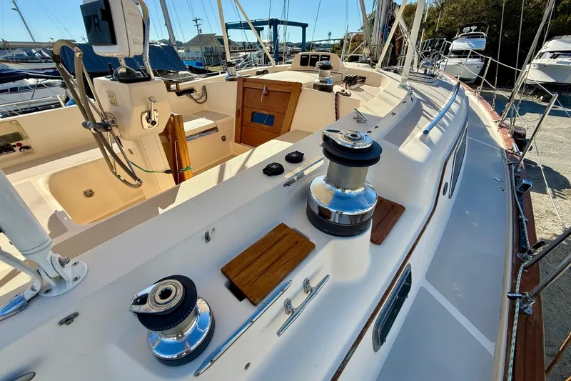 Slide: The Image of 2005 Island Packet 485 sailboat deck with winches and steering wheel in marina setting. - 11