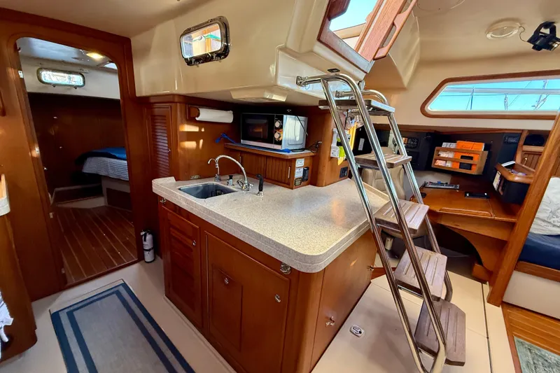 Slide: The Image of Interior of 2005 Island Packet 485 yacht with kitchen, ladder, and cozy cabin space. - 22