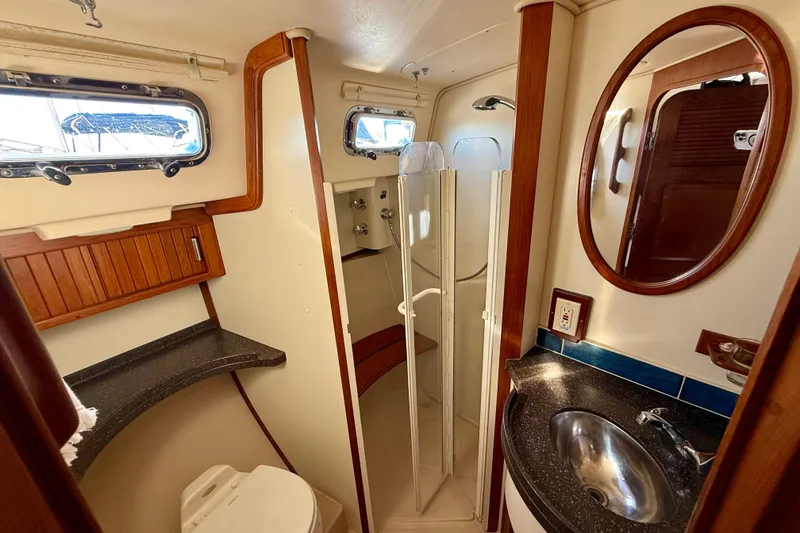 Slide: The Image of 2005 Island Packet 485 yacht bathroom with shower, sink, and wooden accents. - 25