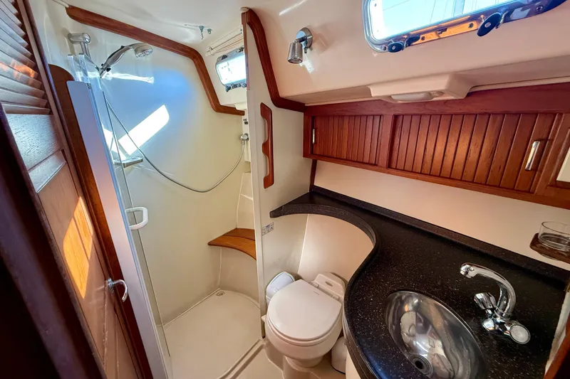 Slide: The Image of Luxurious 2005 Island Packet 485 yacht bathroom with shower, sink, and wooden cabinetry. - 28