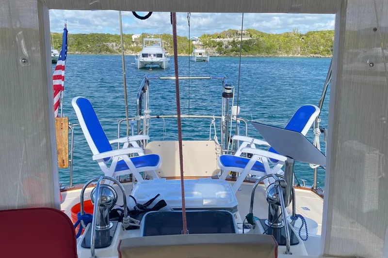 Slide: The Image of Cockpit view of 2005 Island Packet 485 sailboat with blue chairs and scenic water backdrop. - 6