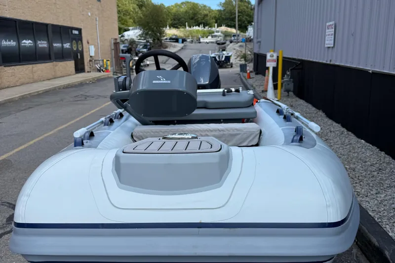 Slide: The Image of 2025 Highfield CL310 FCT inflatable boat parked outdoors, showcasing steering console and seating. - 2