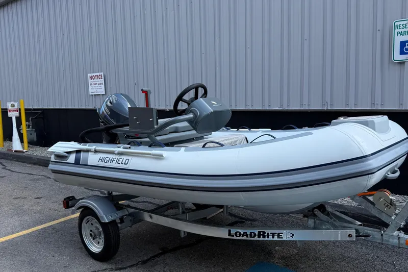 Slide: The Image of 2025 Highfield CL310 FCT inflatable boat on LoadRite trailer, parked by a building. - 9
