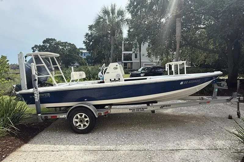 Slide: The Image of 2013 Hewes Redfisher 18 boat on trailer, parked outdoors near palm trees. - 2