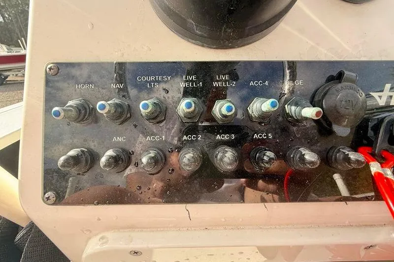 Slide: The Image of Control panel of a 2013 Hewes Redfisher 18 boat with various switches and labels. - 22