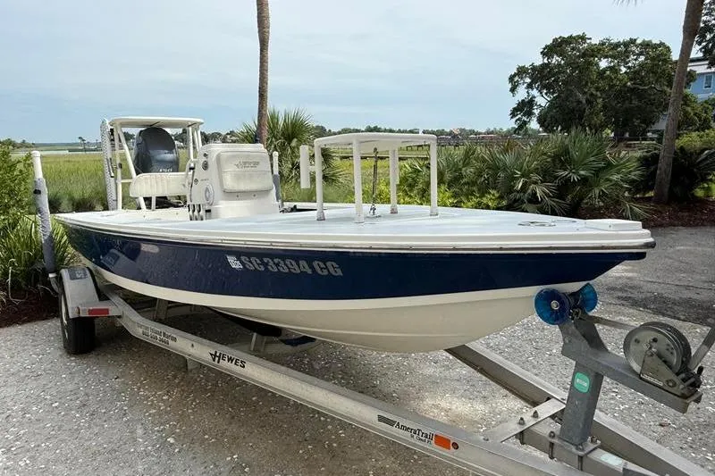 Slide: The Image of 2013 Hewes Redfisher 18 boat on trailer, parked outdoors near lush greenery. - 3