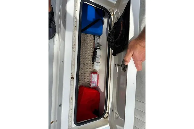 Slide: The Image of Open storage compartment in 2013 Hewes Redfisher 18 boat, containing various items. - 9