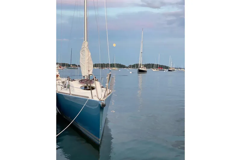 Slide: The Image of Sailboats anchored on calm water at sunset, featuring a 2007 Hallett 33. - 3